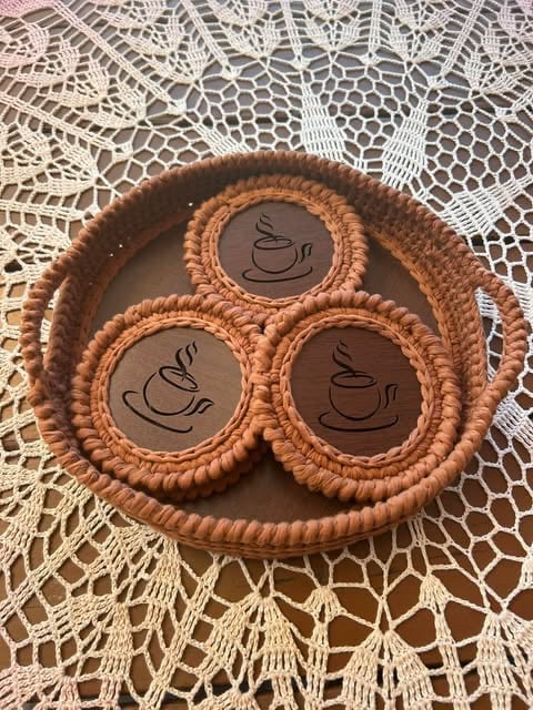 Wooden serving tray with four compartments decorated with coffee cup designs, placed on white lace doily