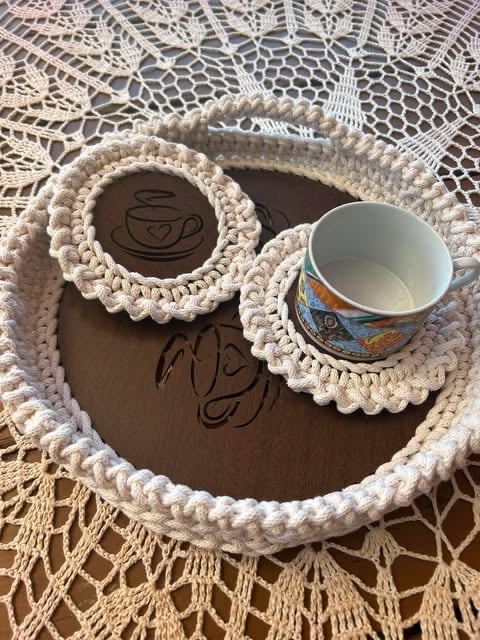 Handmade owl-shaped coaster holder with crocheted beige trim, featuring coffee cup eyes and a small decorative cup on a lace background