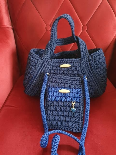 Two crocheted handbags in navy and bright blue with metallic accents, displayed on a red quilted background