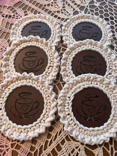 Six chocolate coasters with teacup designs arranged on a lacy doily, featuring cream crocheted borders