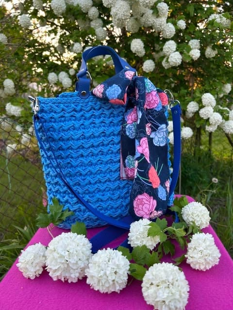 Blue quilted tote bag with floral scarf displayed outdoors surrounded by white hydrangea flowers